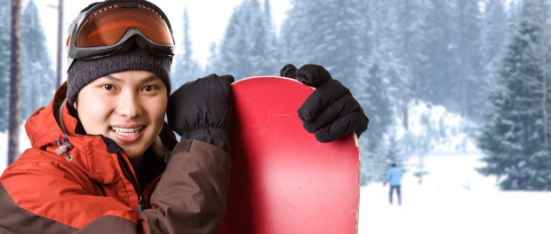 A shot of an asian snowboarder at a ski resort