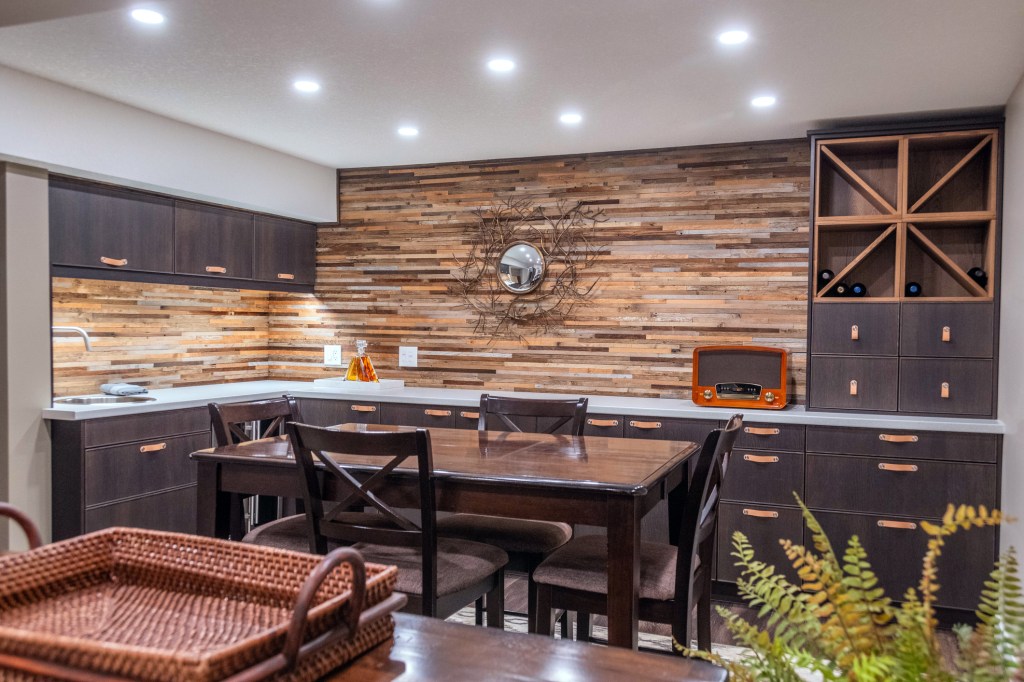 Basement with sink, wood cabinets, vinyl flooring, reclaimed wood backsplash and a games table.