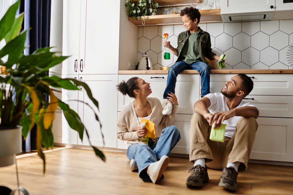 Parents and their son share a joyful moment while cleaning together in their cozy kitchen.